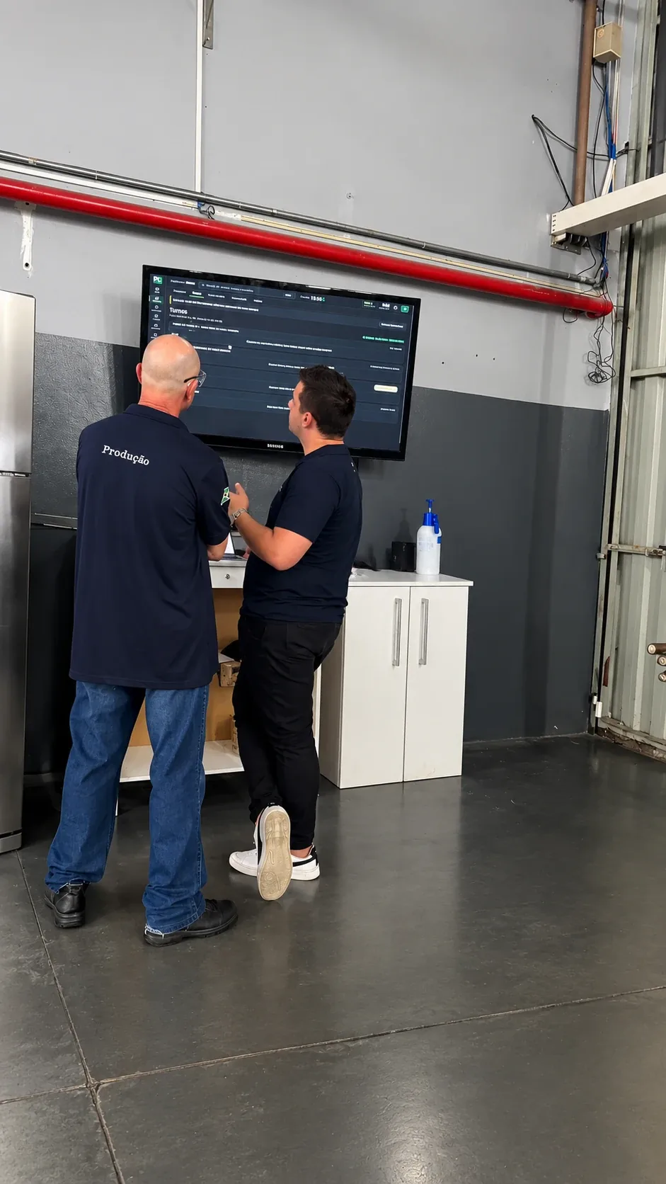 Consultor da A2M orientando um colaborador da produção diante do painel